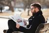 man-glasses-sitting-reading-newspaper-city