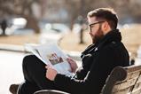 man-glasses-sitting-reading-newspaper-city