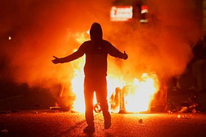 Fire burns near a demonstrator as riots continue in Ballymena, Northern Ireland