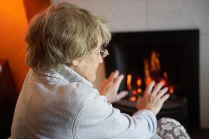 Pensioner warming herself in front of a fire